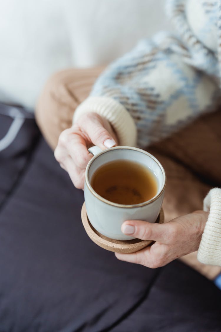 Crop Woman Enjoying Aromatic Tea On Couch