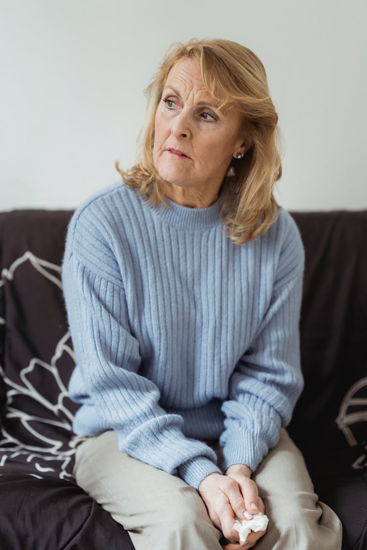 Lonely Mature Woman Looking Away Sadly Sitting On Sofa