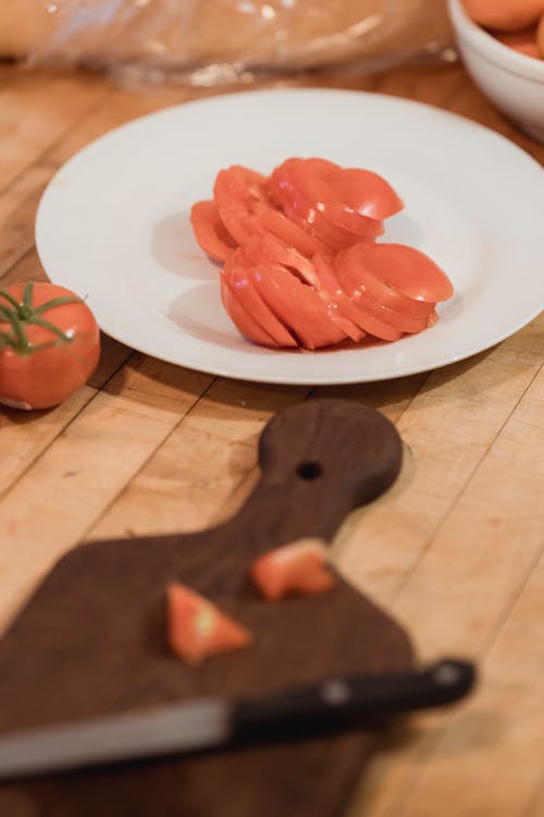 Sliced ripe tomatoes on plate placed near cutting board