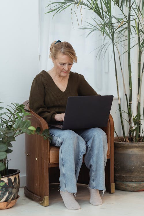 Focused mature woman working on laptop on chair