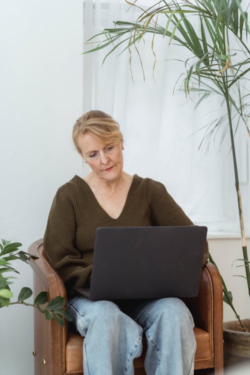 Thoughtful mature woman working on laptop in living room