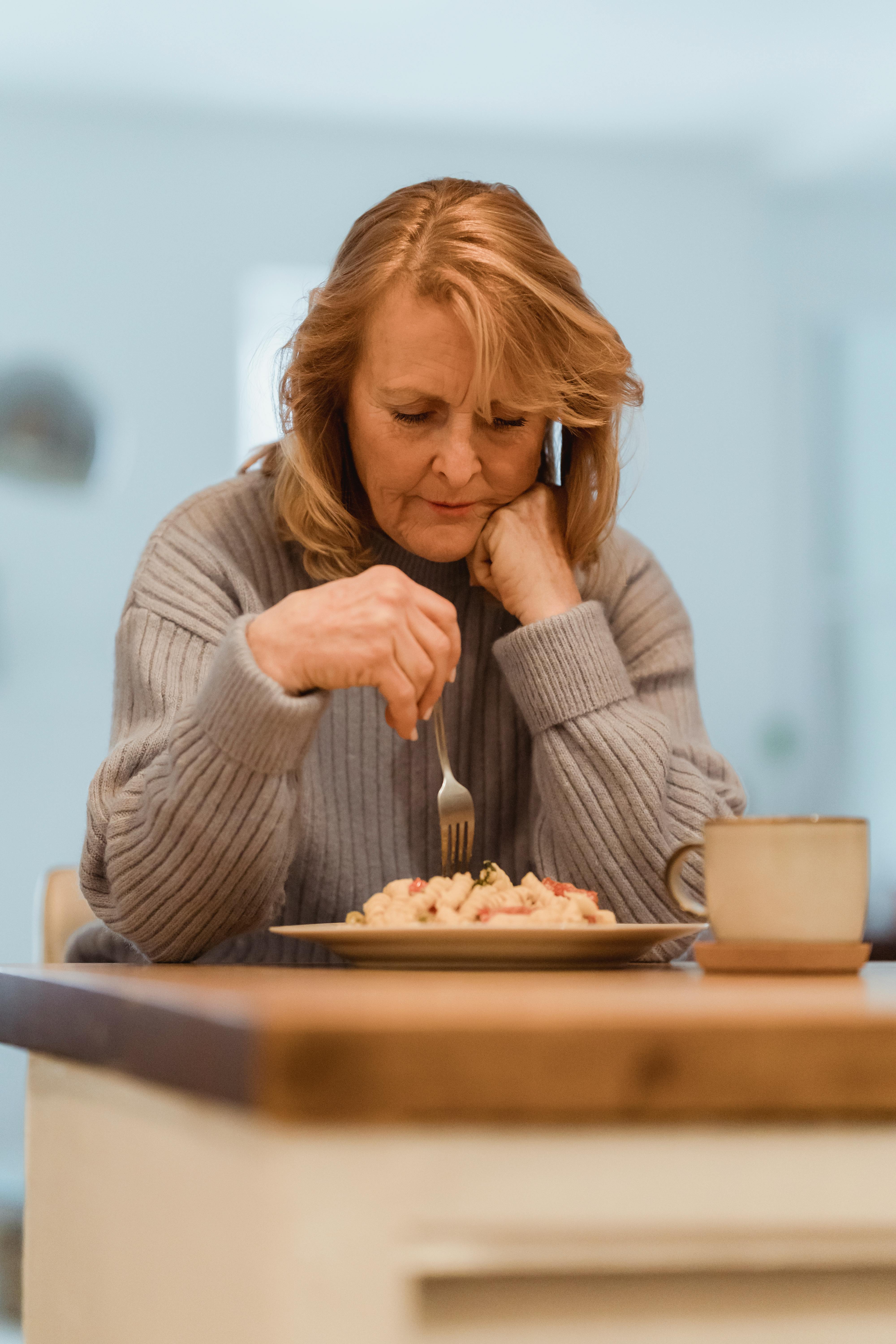 focused mature woman eating freshly cooked pasta