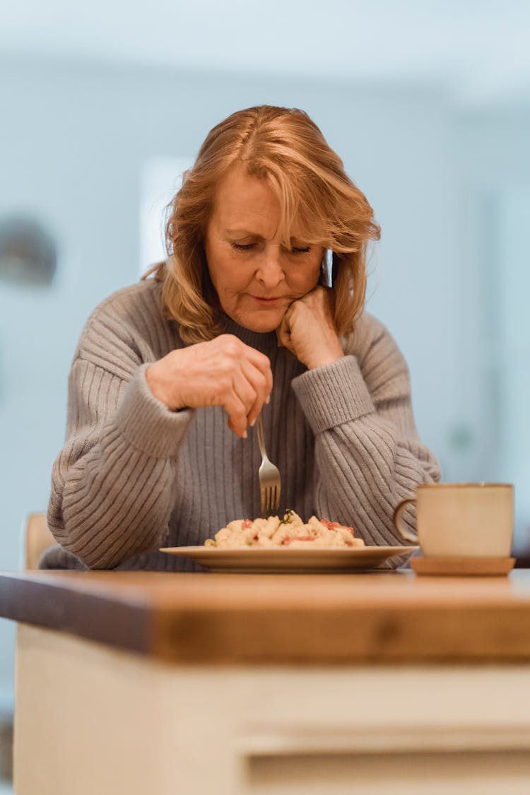 Focused Mature Woman Eating Freshly Cooked Pasta