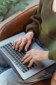 Close-up of a woman typing on a laptop, creating a cozy and productive atmosphere at home.