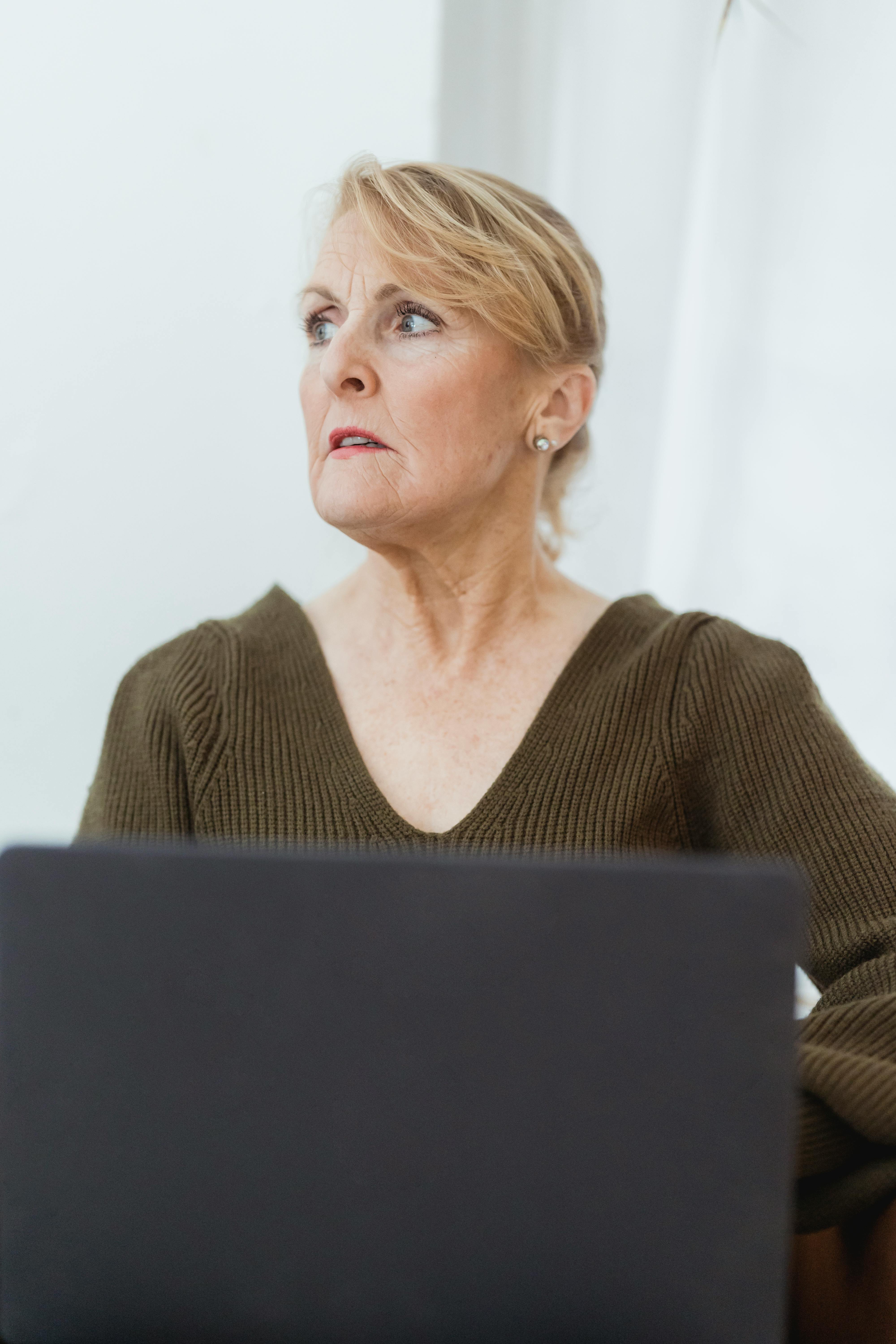 thoughtful mature woman working on laptop