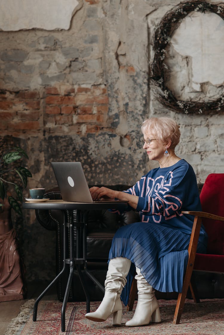 A Fashionable Elderly Woman Working On A Laptop