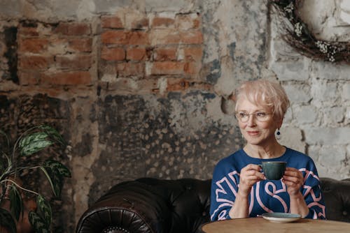 Photo of an Elderly Woman in a Blue Top Holding a Cup