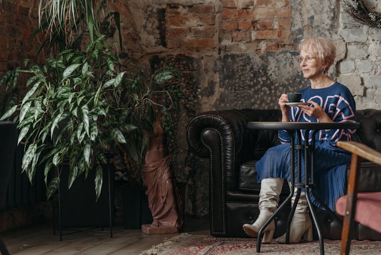 Elegant Senior Woman Sitting At A Table In A Stylish Cafe