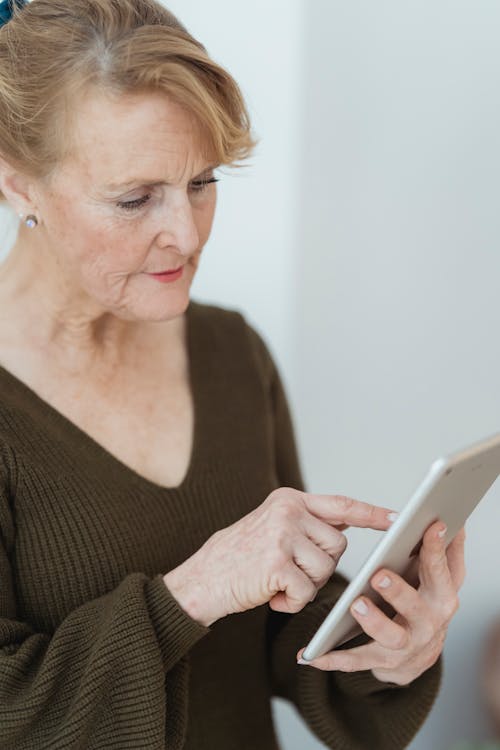 Free Crop pensive mature woman browsing tablet Stock Photo