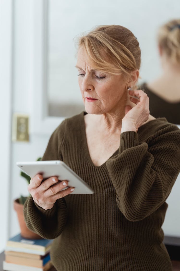 Thoughtful Mature Woman Using Tablet And Touching Neck