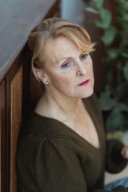 Free Concerned mature woman standing against wall in room Stock Photo