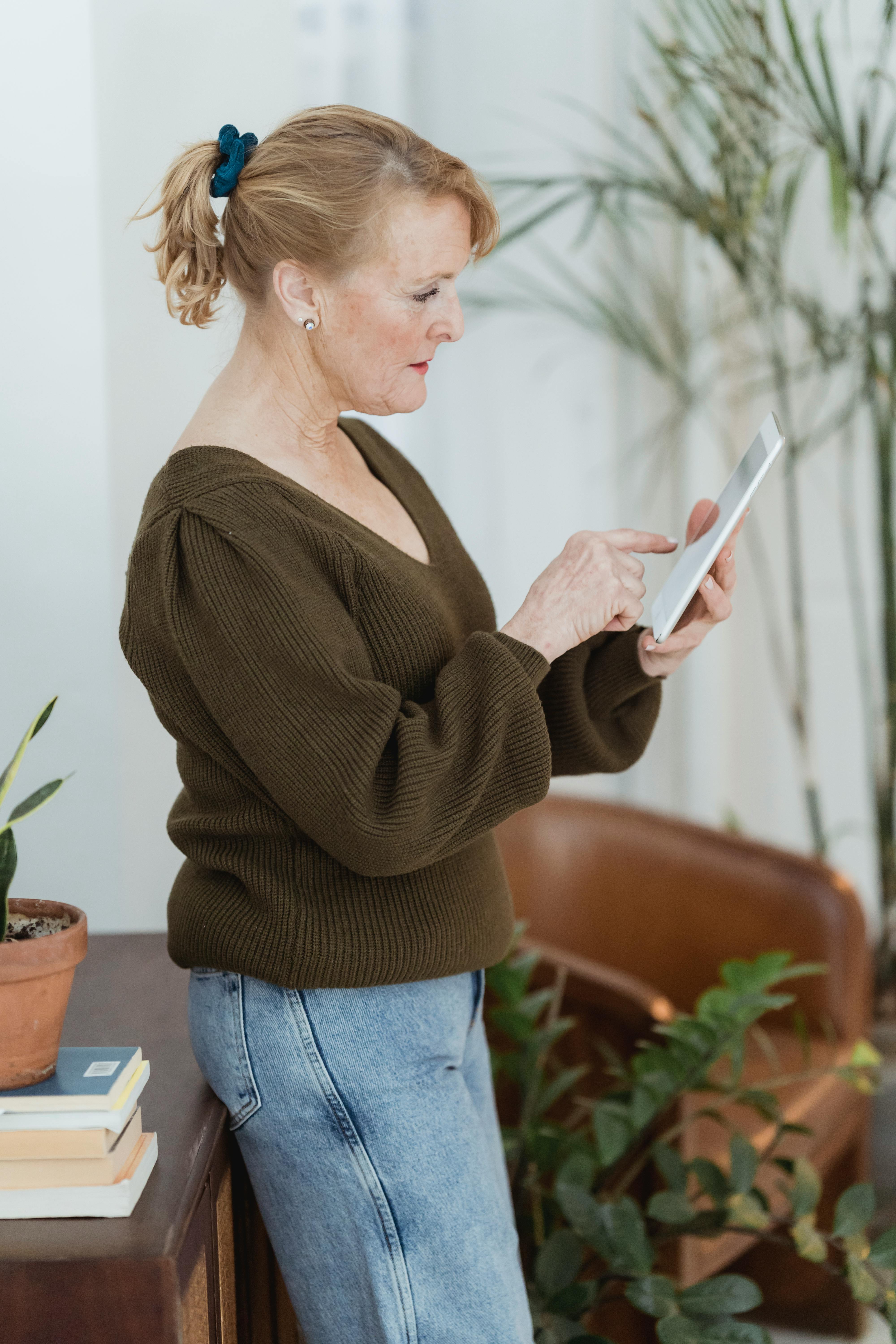 Focused mature woman using tablet in living room · Free Stock Photo