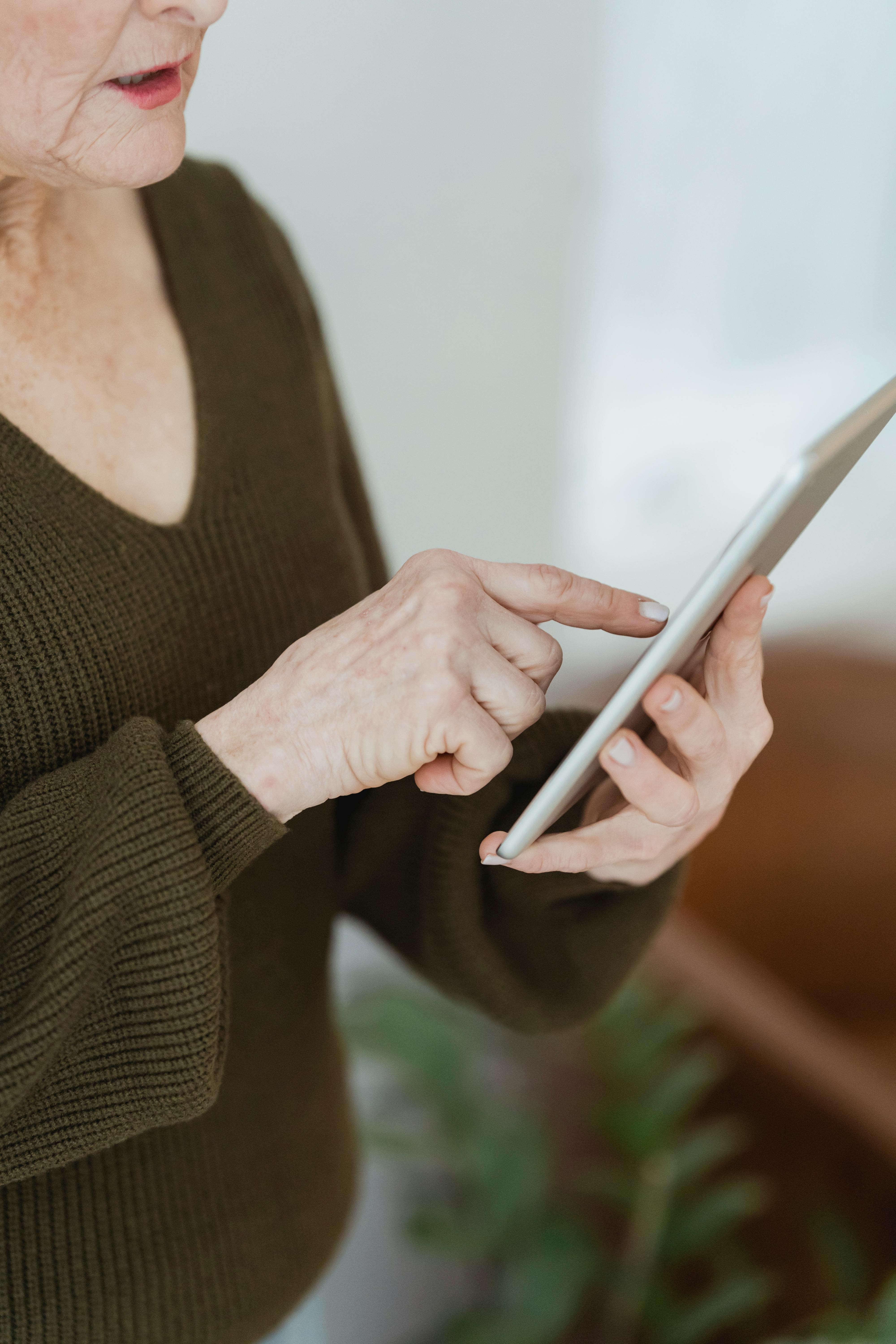 crop senior woman touching screen on smartphone at home