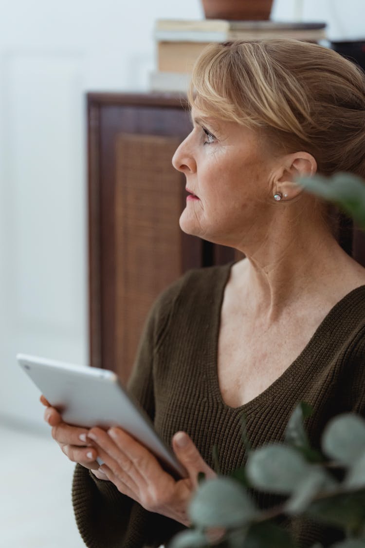 Wistful Woman With Smartphone In House Room