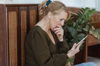 Amazed senior woman with smartphone in house room