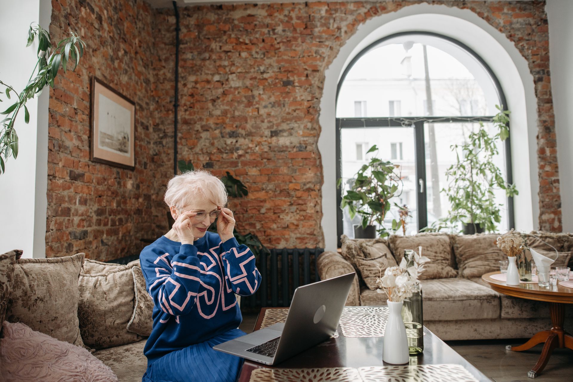 Elderly woman works on a laptop in a stylish home office setting.