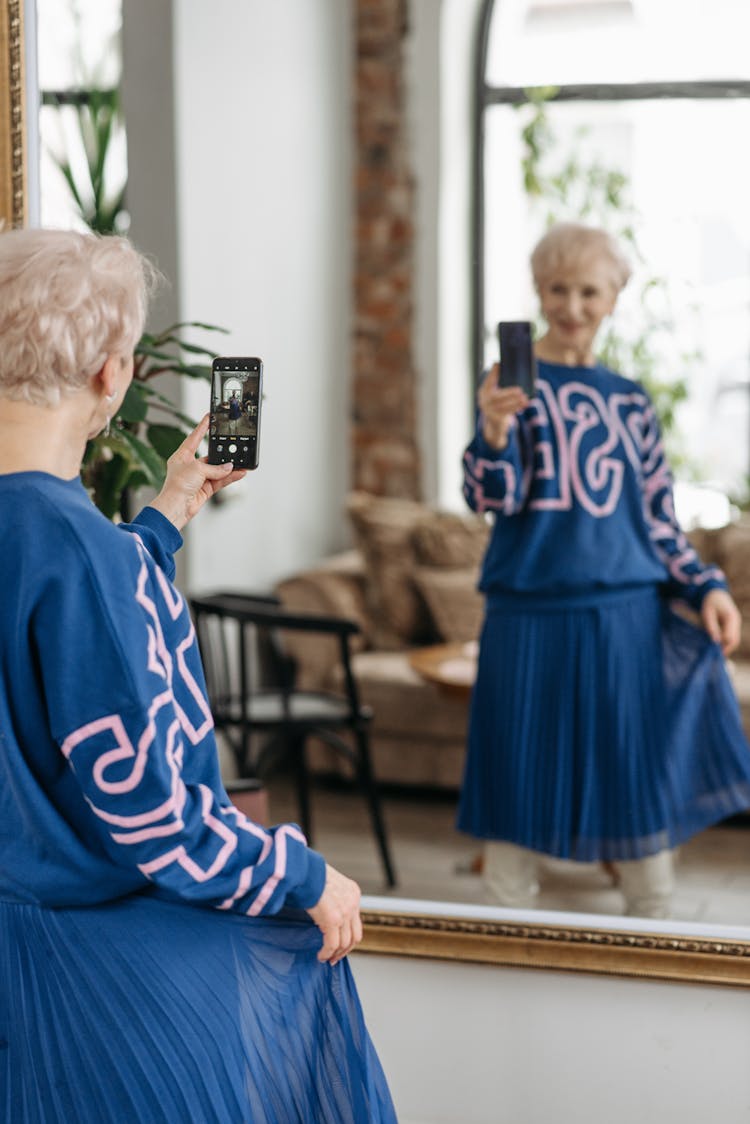 Elderly Woman In Blue Clothes Taking Selfie In Mirror