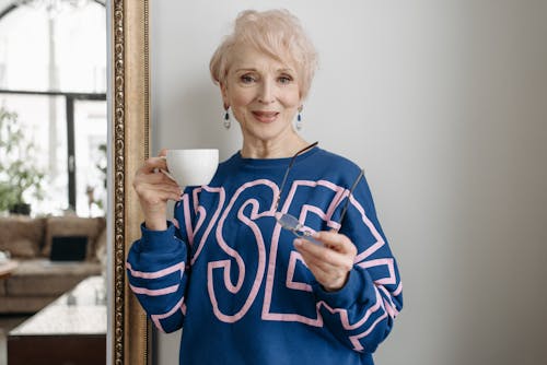 
Elderly Woman in Blue Long Sleeve Shirt Holding Coffee Cup