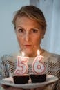 Mature woman with delicious muffins and burning number candles