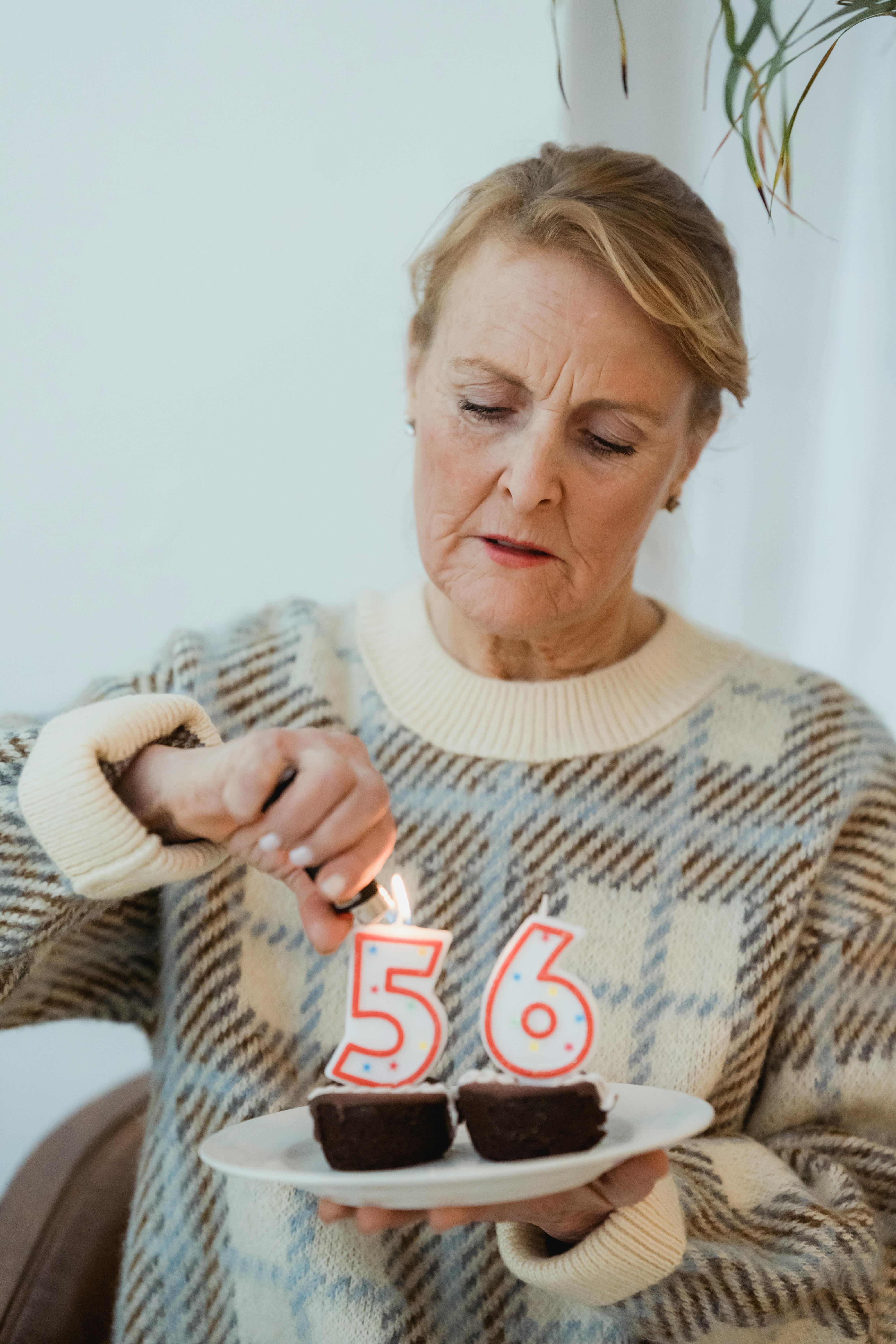 mature woman lightning candles on birthday cupcakes