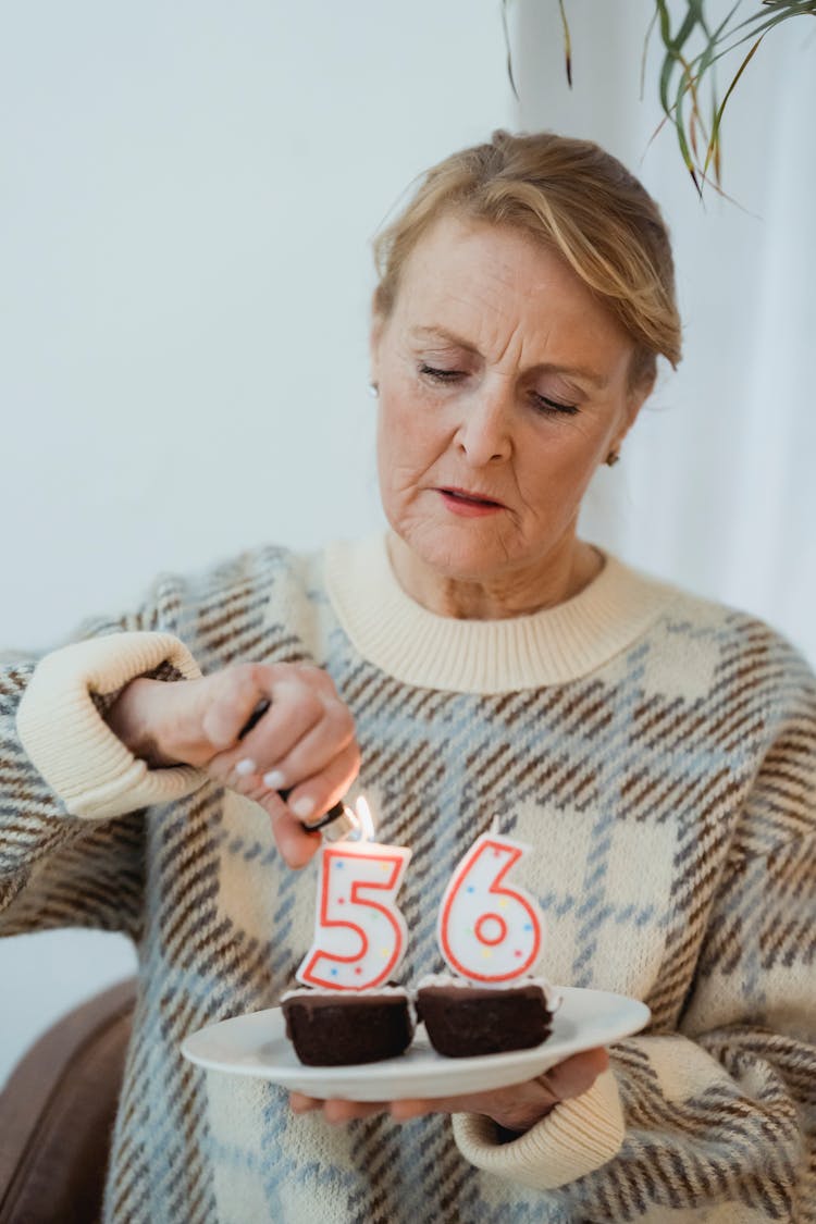 Mature Woman Lightning Candles On Birthday Cupcakes