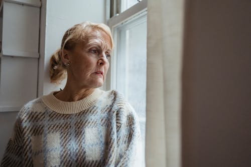 Pondering mature woman looking out window