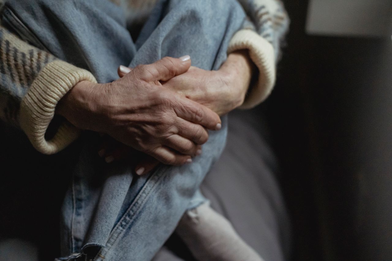 crop unrecognizable mature female wearing jeans and sweater embracing