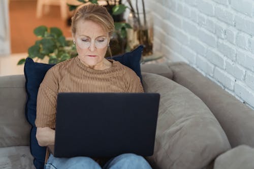 Serious mature woman working on laptop on sofa