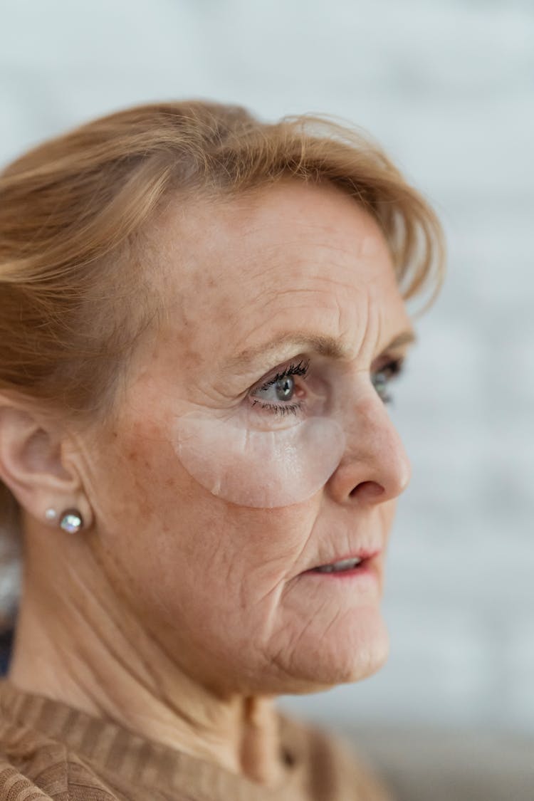 Crop Mature Woman With Eye Patches Looking Away Pensively