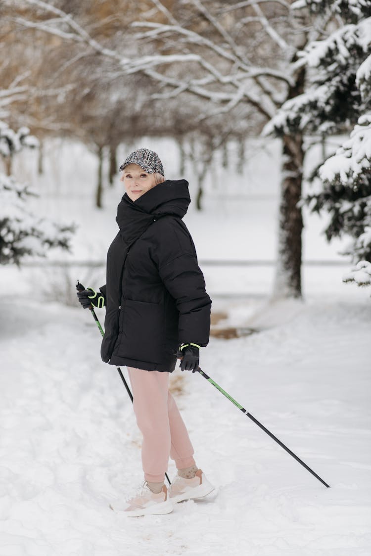 An Elderly Woman In Pink Pants Standing On White Snow