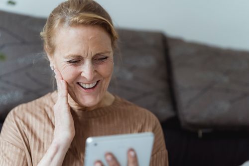 Free A senior woman with a warm smile using a tablet indoors, enjoying a moment. Stock Photo