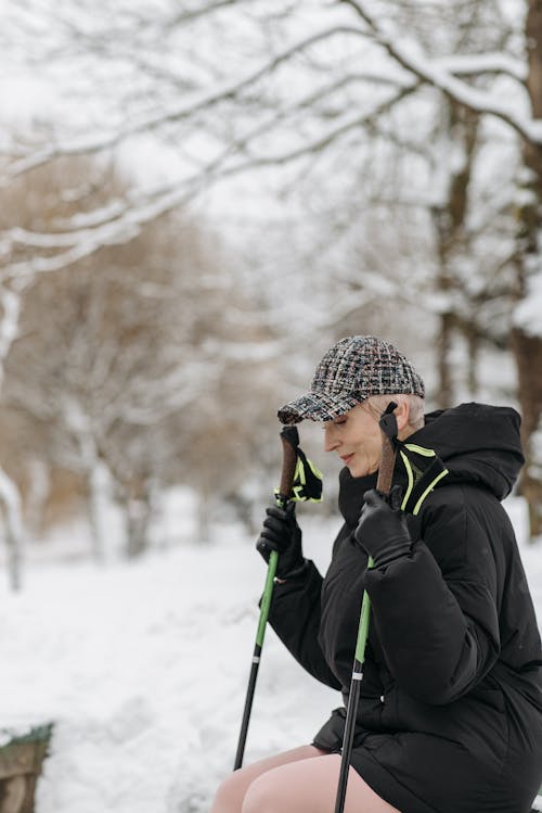 Photo of an Elderly Woman in a Black Jacket Holding Trekking Poles