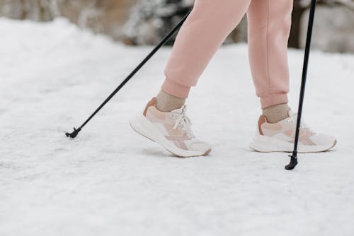 A Person Wearing Sneakers Walking on the Snow Covered Ground