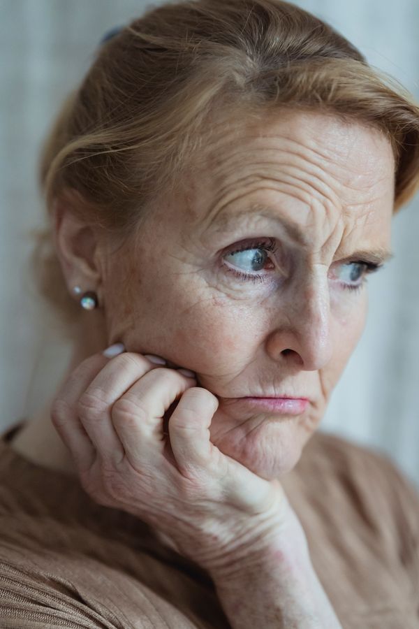 Mature woman with worried, confused expression, hand on chin