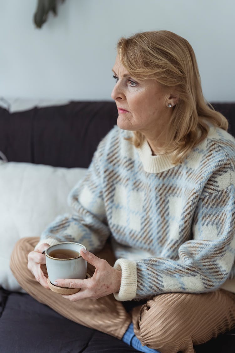 Woman Sitting Crossed Legged On The Sofa And Drinking Tea 