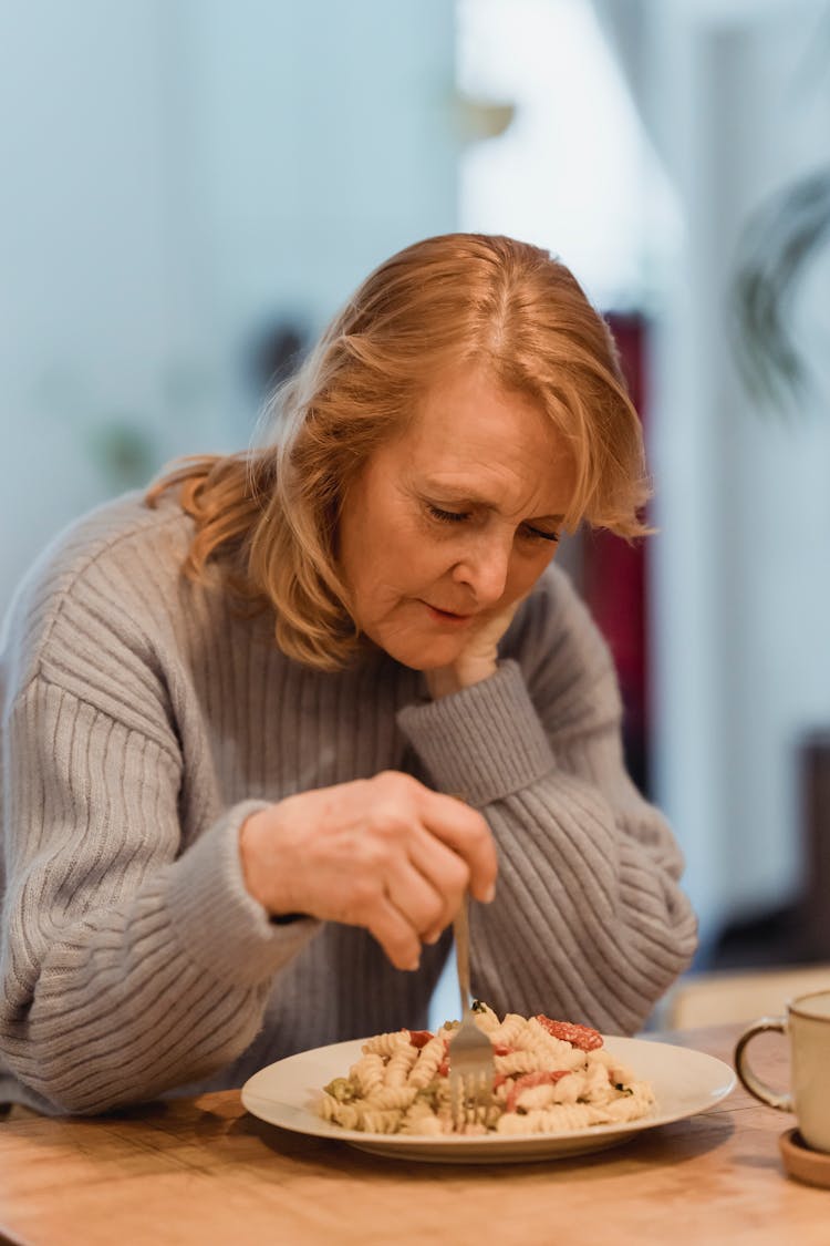 An Elderly Woman Eating Pasta Alone