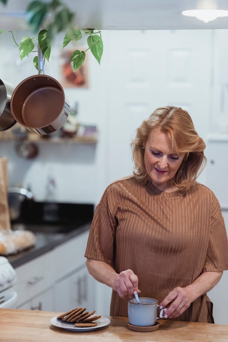 Senior Woman Stirring Drink In Kitchen