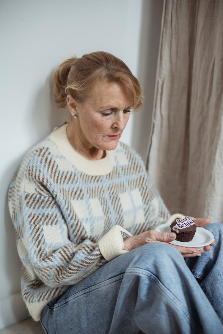 Unhappy Senior Woman With Birthday Cupcake In Room