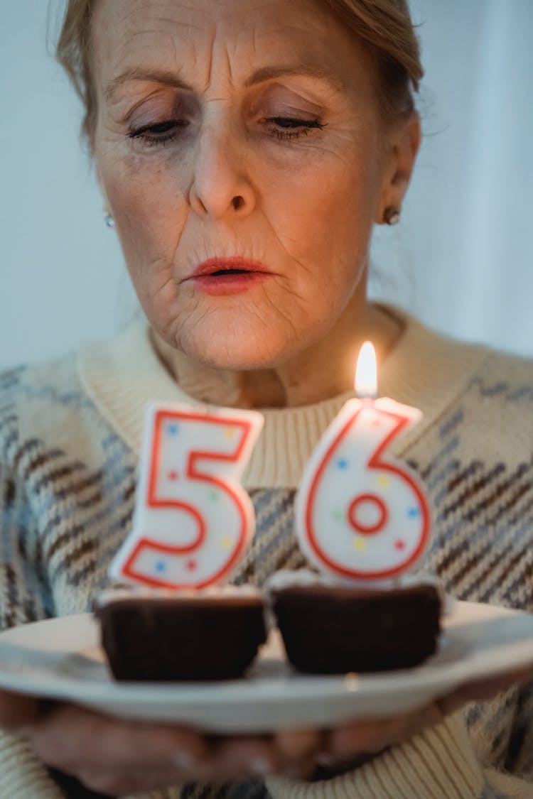 Mature Woman Blowing Candles During Birthday Celebration