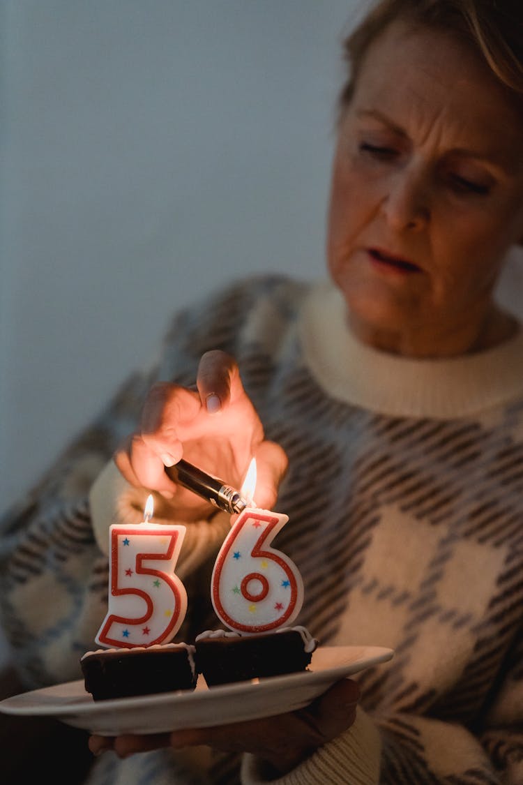 Senior Woman Lighting Candles On Birthday Cupcakes