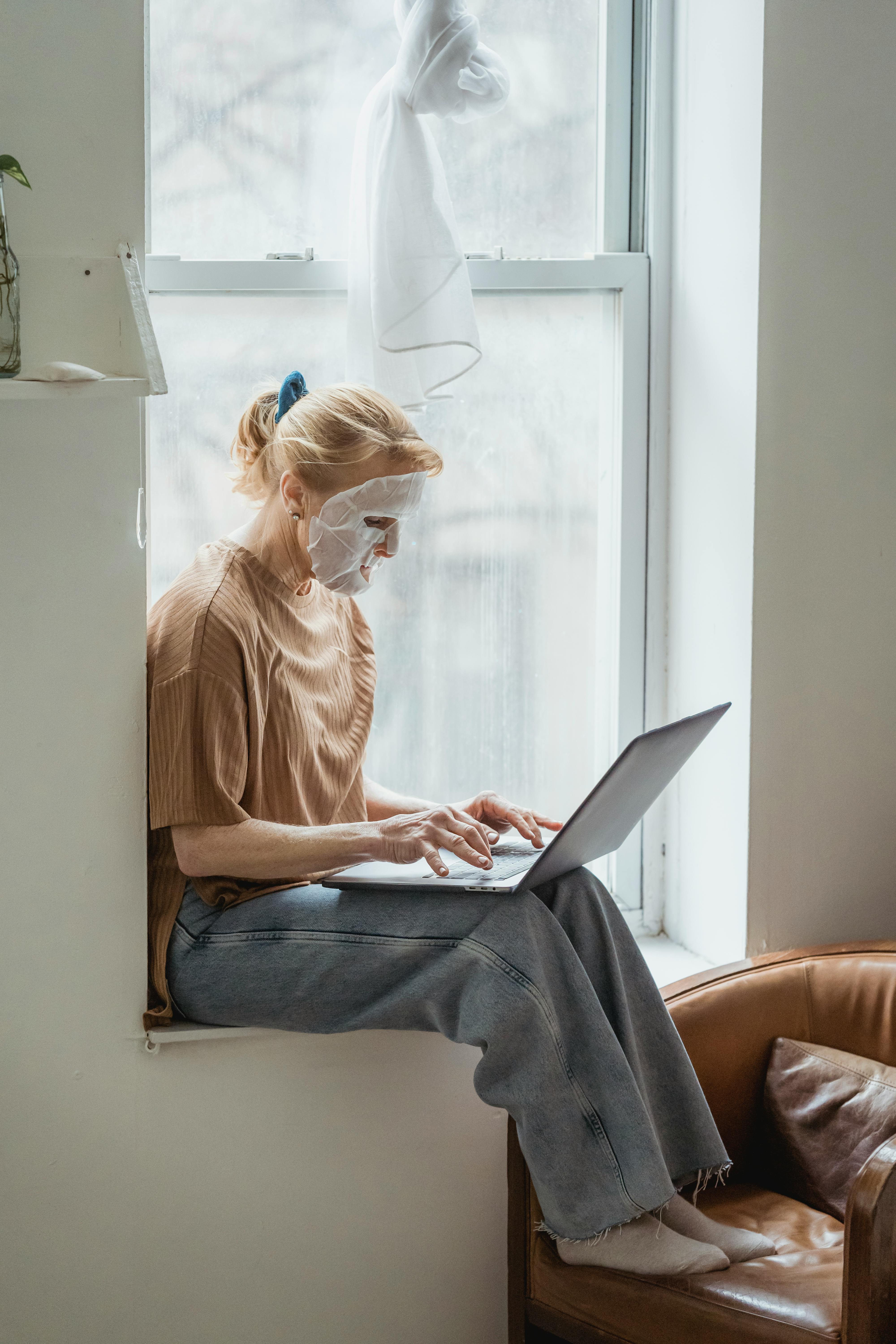 senior woman in facial mask using laptop