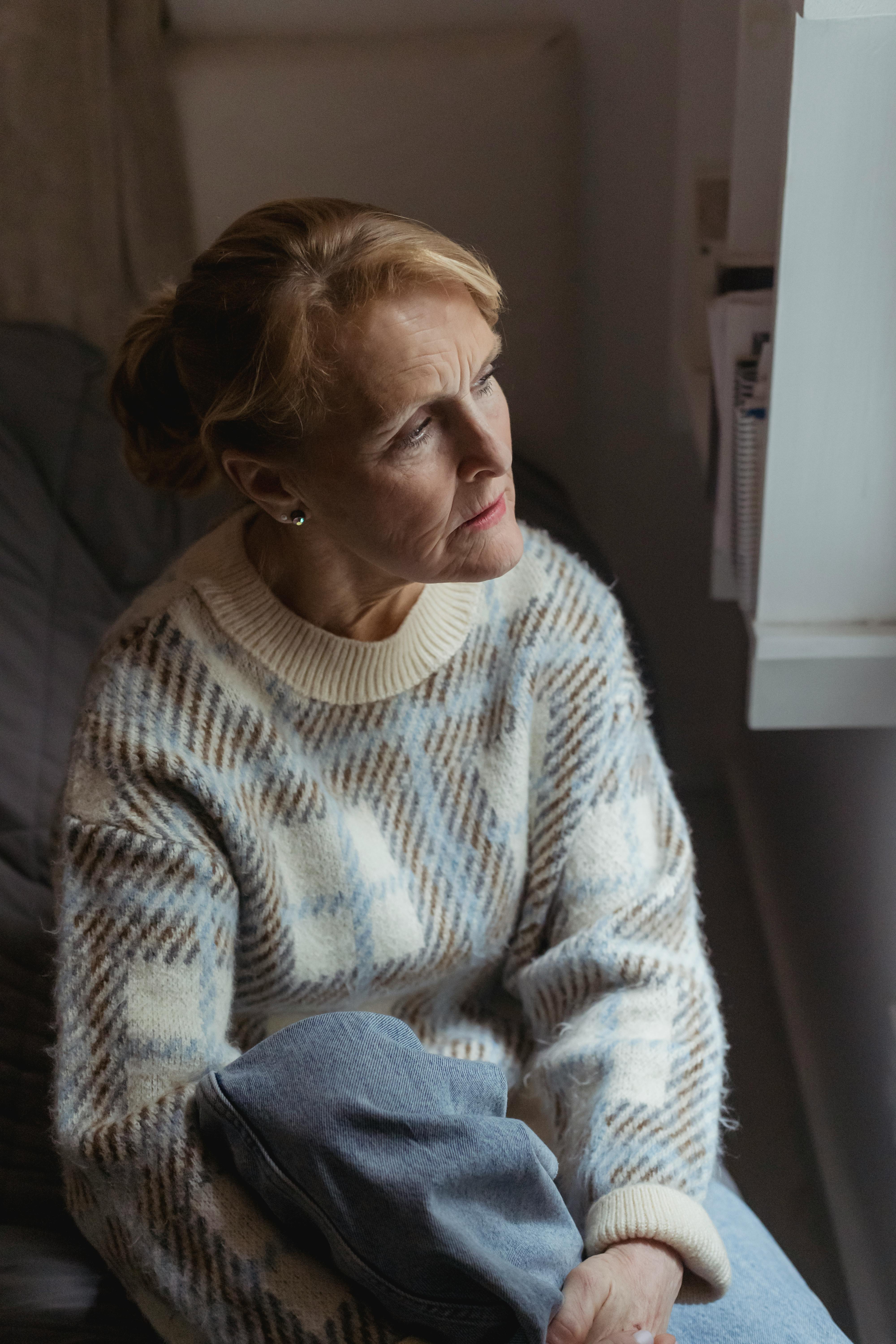 pensive senior woman sitting in room