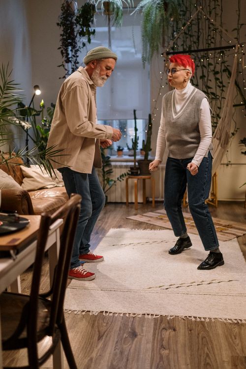 Free Senior couple enjoying a joyful dance in their warmly decorated living room. Stock Photo