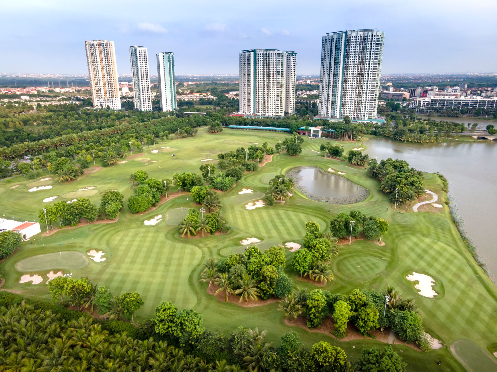Aerial shot of a lush golf course with towering skyscrapers in Ho Chi Minh City, Vietnam.