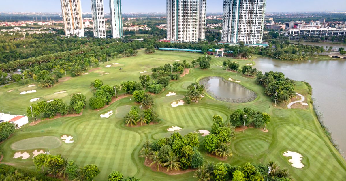 Aerial shot of a lush golf course with towering skyscrapers in Ho Chi Minh City, Vietnam.