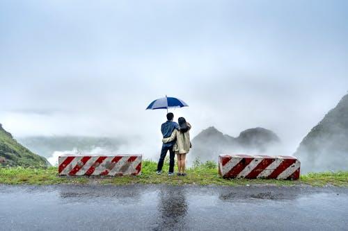 A Sweet Couple Standing on the Cliff Near Concrete Barriers 