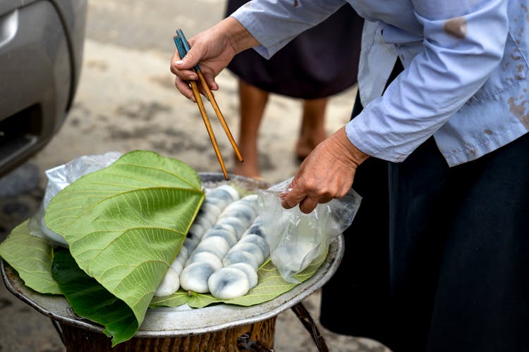 Close-u Of A Woman Packing Jilledu Kayalu Into A Bag Using Chopsticks 