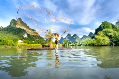 Free Man Throwing a Fishing Net While Standing on a Raft  Stock Photo