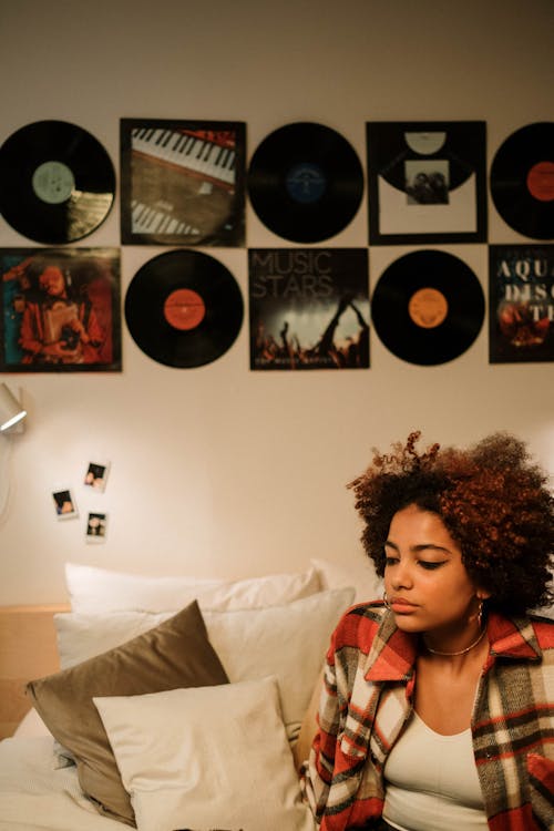 Woman with Curly Hair Sitting Near Vinyl Records