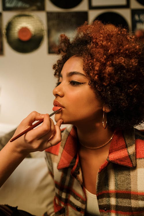 Photo of a Person's Hand Applying Makeup to a Woman's Face